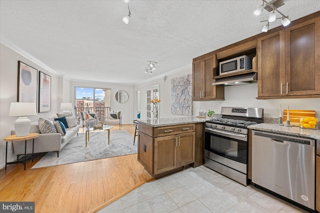 kitchen featuring a peninsula, appliances with stainless steel finishes, open floor plan, and crown molding