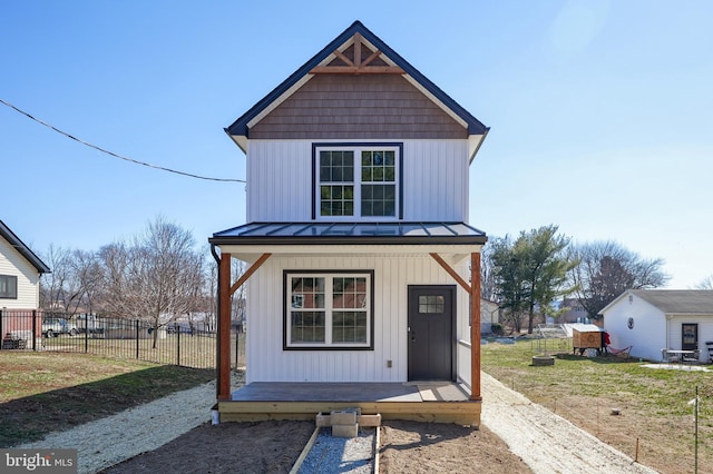 view of front of home with an outbuilding, board and batten siding, a standing seam roof, fence, and metal roof