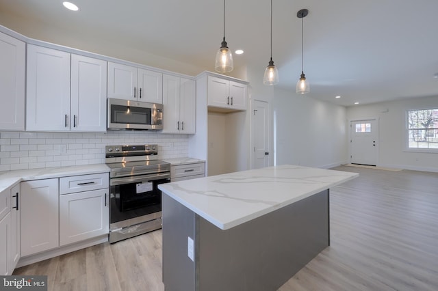 kitchen featuring tasteful backsplash, appliances with stainless steel finishes, open floor plan, a center island, and white cabinetry