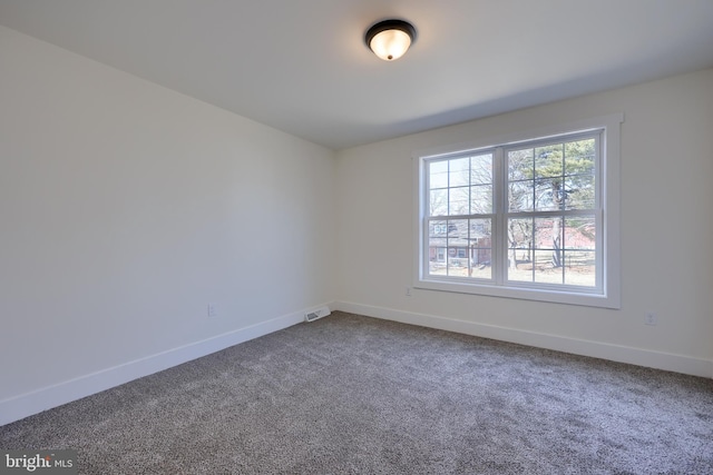 empty room with carpet, visible vents, and baseboards