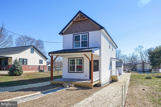 view of front of house with covered porch, board and batten siding, a standing seam roof, fence, and metal roof