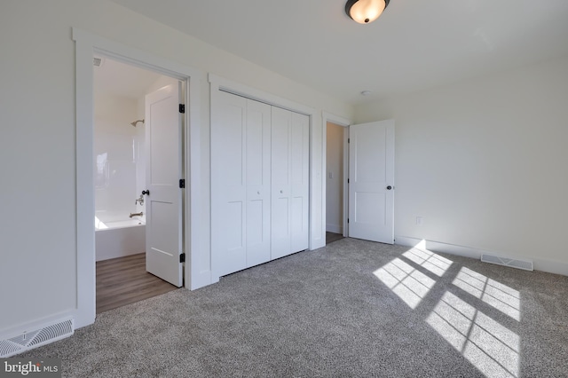 unfurnished bedroom featuring connected bathroom, a closet, visible vents, and carpet flooring