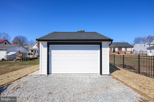 garage with gravel driveway and fence