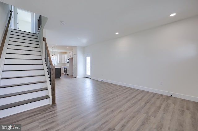 unfurnished living room with light wood-style floors, recessed lighting, stairway, and baseboards