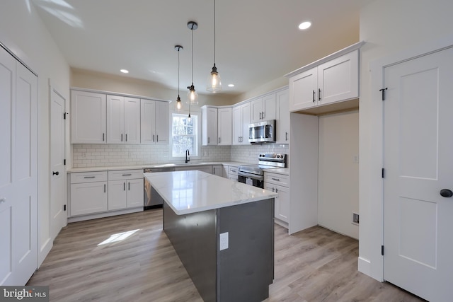 kitchen with stainless steel appliances, backsplash, a sink, and white cabinetry