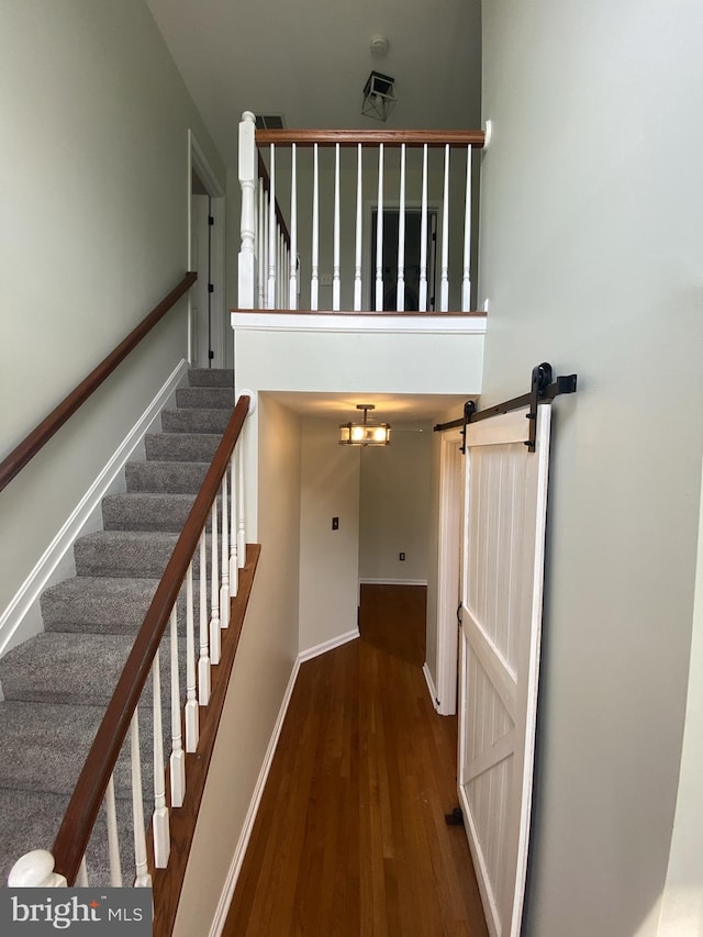 stairway featuring a towering ceiling, baseboards, and wood finished floors