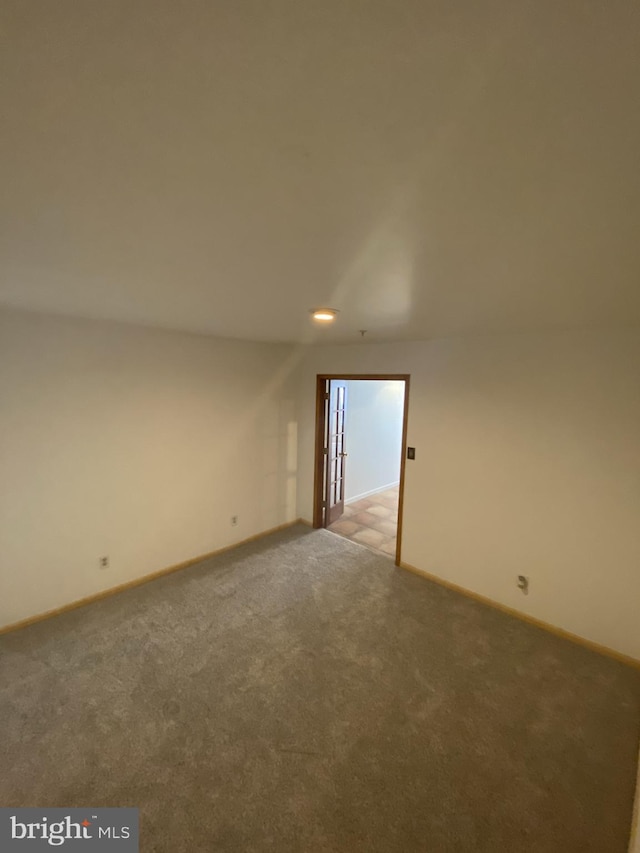 unfurnished room featuring carpet floors and baseboards