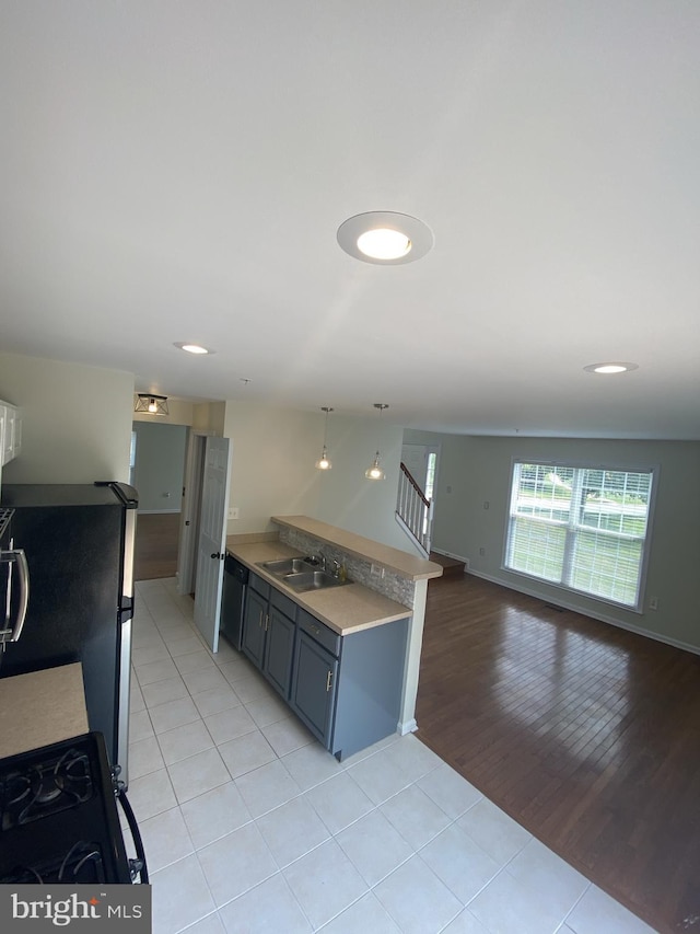kitchen with light tile patterned floors, a peninsula, a sink, open floor plan, and black appliances