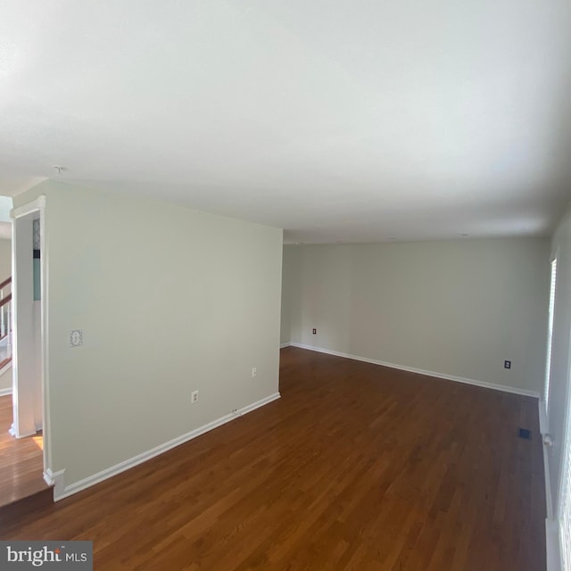 spare room with dark wood-style floors and baseboards