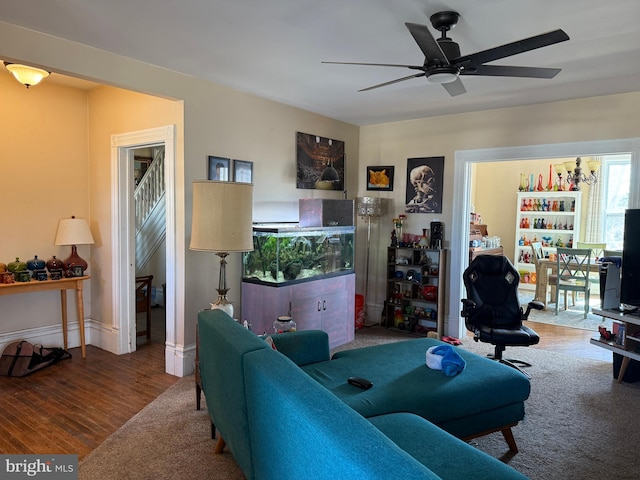 living area with baseboards, ceiling fan, and wood finished floors