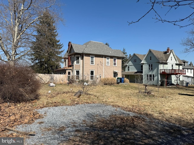 back of house with a deck, fence, and a chimney