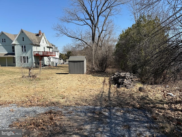 view of yard featuring an outbuilding, a wooden deck, and a storage unit