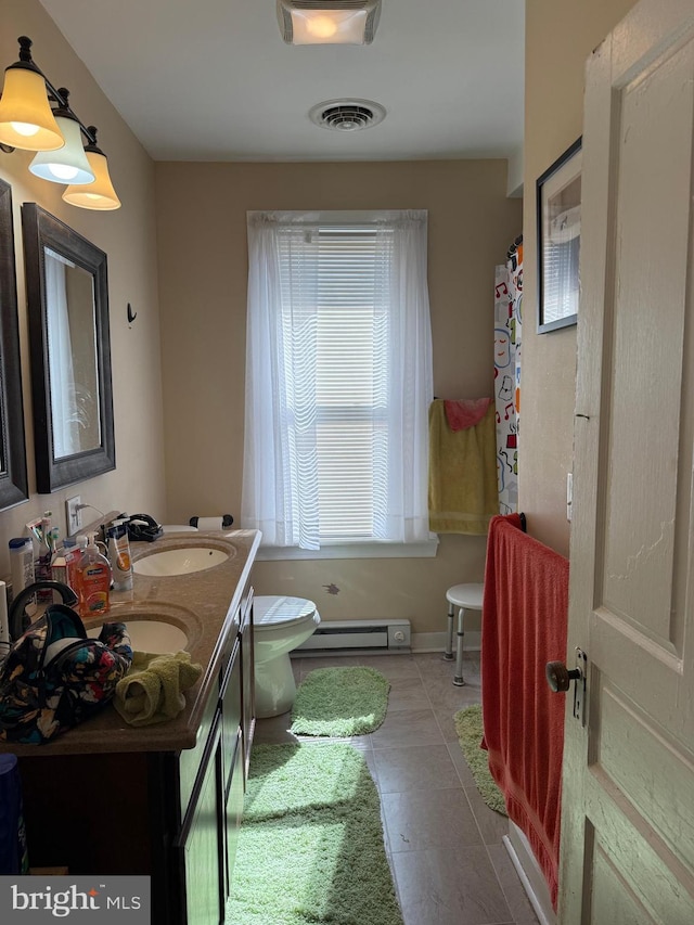 bathroom with visible vents, toilet, a sink, double vanity, and baseboard heating