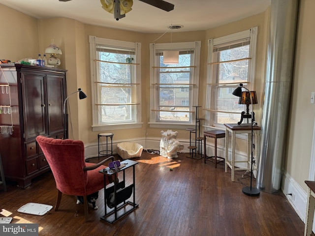 living area with dark wood-style floors, a ceiling fan, visible vents, and a wealth of natural light