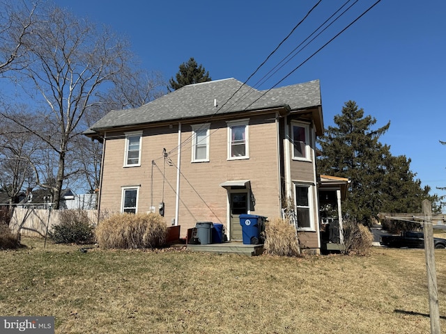 rear view of house with a yard and a shingled roof