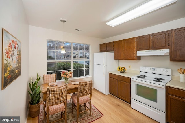 kitchen with under cabinet range hood, white appliances, visible vents, light countertops, and light wood-type flooring