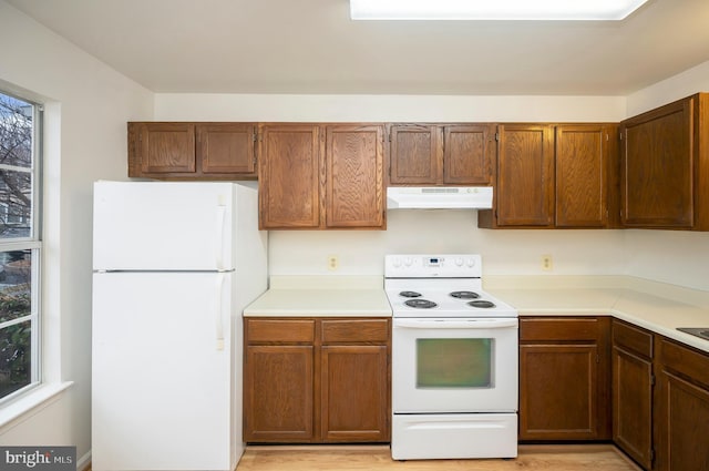 kitchen featuring light countertops, white appliances, brown cabinets, and under cabinet range hood