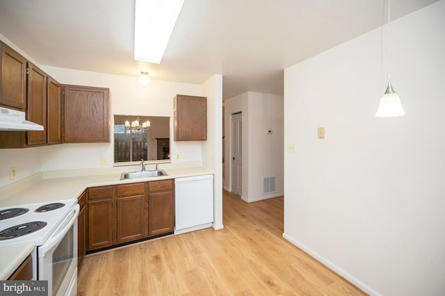 kitchen featuring visible vents, light wood-style flooring, a sink, white appliances, and under cabinet range hood