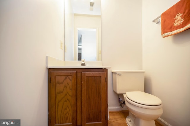 bathroom with visible vents, toilet, vanity, wood finished floors, and baseboards