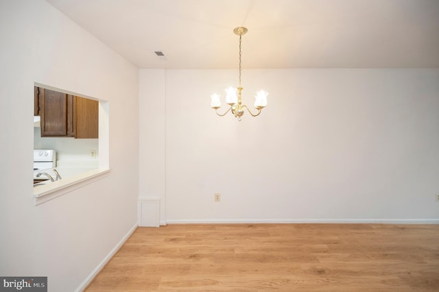 unfurnished dining area with light wood-style floors, baseboards, and a notable chandelier