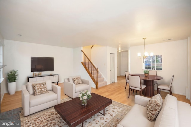 living area featuring stairs, light wood finished floors, visible vents, and a notable chandelier