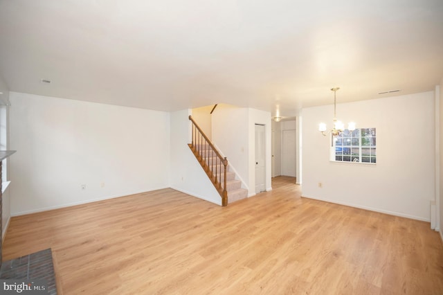 spare room featuring a notable chandelier, visible vents, baseboards, stairs, and light wood-type flooring