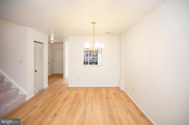 unfurnished dining area with light wood finished floors, baseboards, stairs, and a chandelier