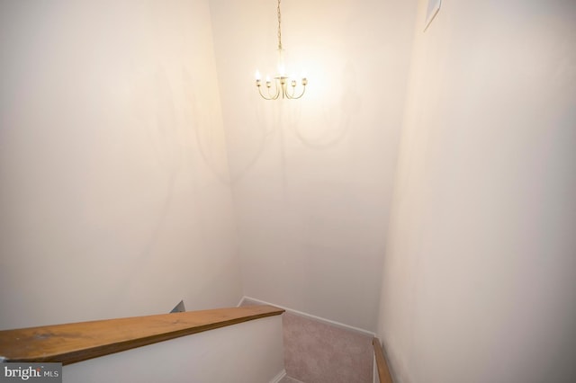 stairway featuring carpet, baseboards, and a notable chandelier