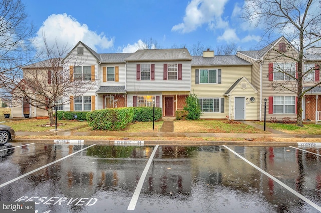 multi unit property with uncovered parking, a chimney, and brick siding