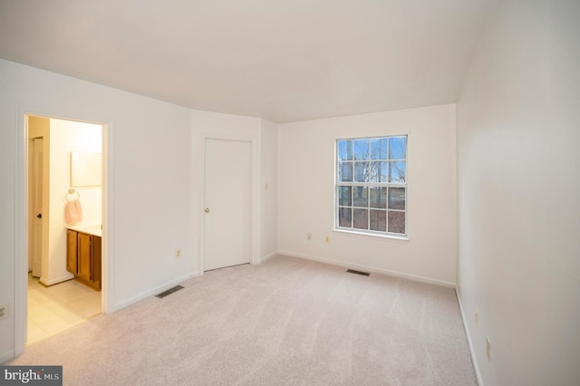 unfurnished bedroom featuring baseboards, visible vents, and light colored carpet