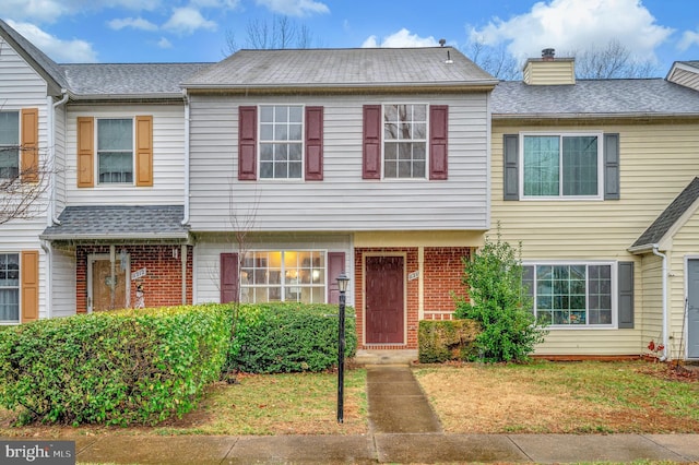 townhome / multi-family property featuring a chimney and brick siding