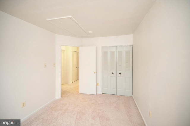 unfurnished bedroom featuring carpet floors, attic access, baseboards, and a closet