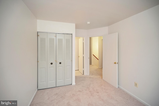 unfurnished bedroom with carpet floors, baseboards, and a closet