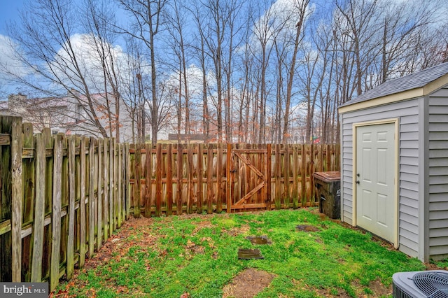 view of yard featuring a storage unit, a gate, central AC, a fenced backyard, and an outdoor structure