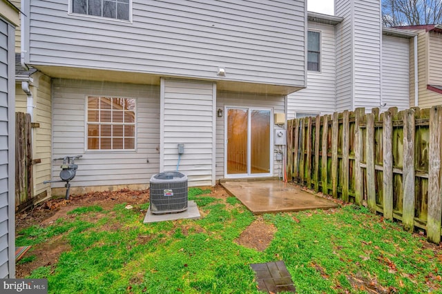 view of exterior entry with a patio area, fence, and central air condition unit