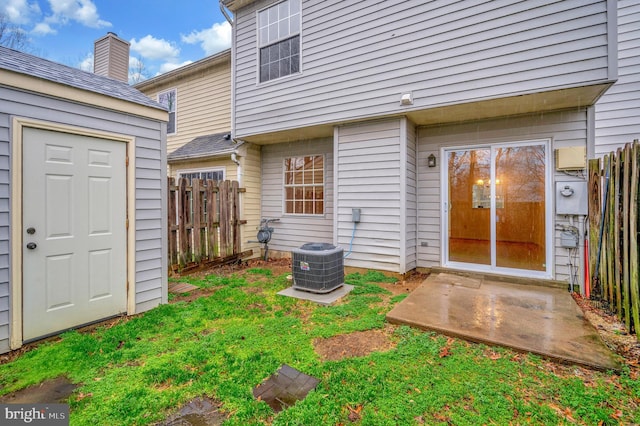 property entrance featuring central air condition unit, fence, and a yard