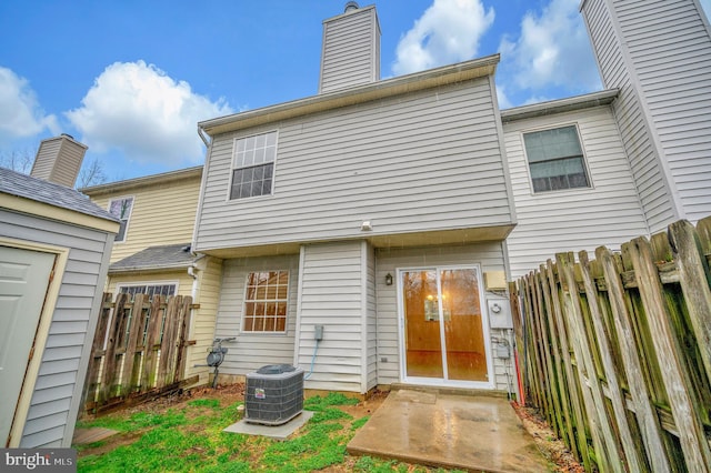 rear view of house featuring a chimney, fence, and central AC unit