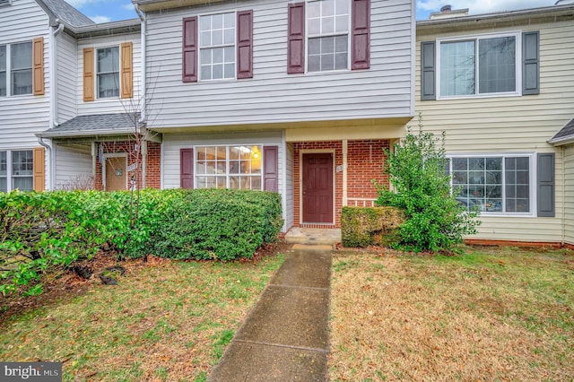 townhome / multi-family property with a front lawn and brick siding