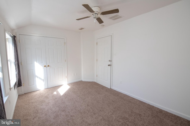 unfurnished bedroom featuring carpet floors, lofted ceiling, visible vents, and a closet