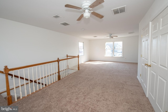carpeted empty room featuring baseboards, a ceiling fan, and visible vents