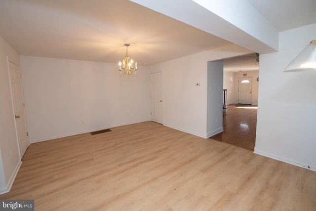 unfurnished dining area featuring baseboards, a notable chandelier, visible vents, and light wood-style floors