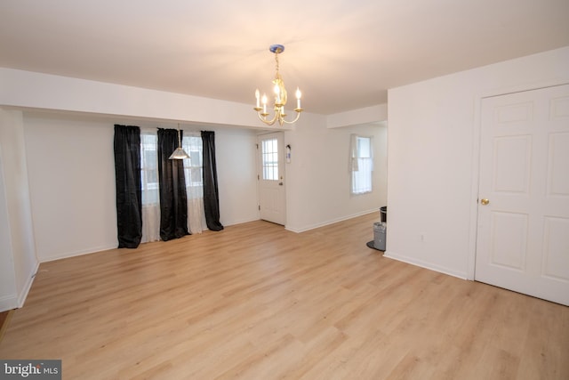 spare room featuring baseboards, a notable chandelier, and light wood-style flooring