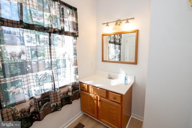 bathroom with vanity, baseboards, wood finished floors, and visible vents