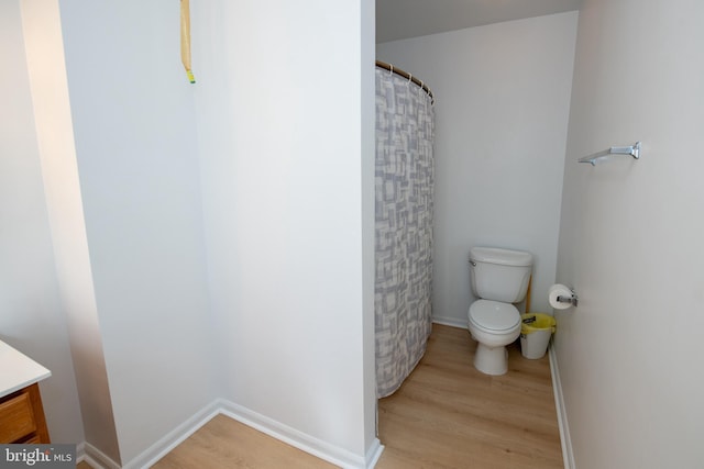 full bath featuring wood finished floors, curtained shower, vanity, baseboards, and toilet