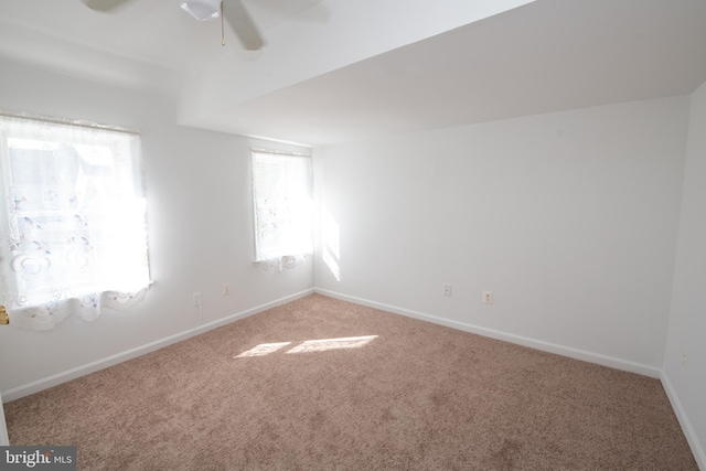 carpeted empty room featuring ceiling fan and baseboards