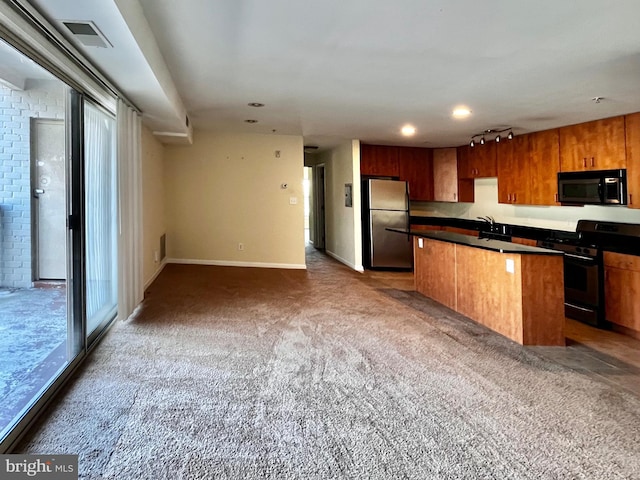 kitchen with carpet, dark countertops, appliances with stainless steel finishes, open floor plan, and a kitchen island