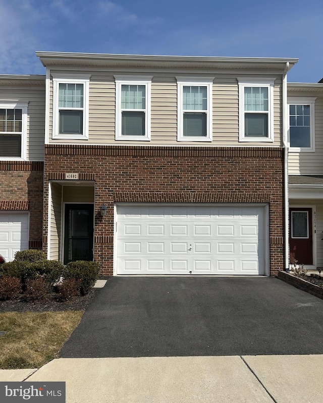 multi unit property featuring aphalt driveway, an attached garage, and brick siding