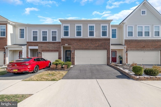 multi unit property with brick siding, driveway, and a garage