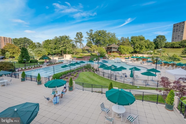 view of property's community with fence, a pool, and a lawn