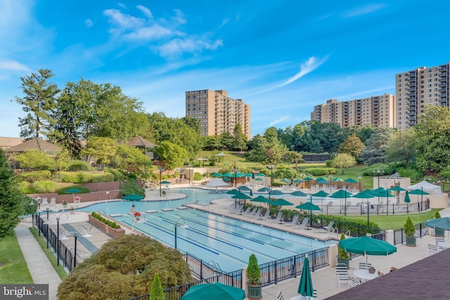 community pool featuring a view of city and fence